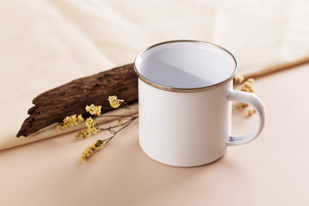 Close-up of a white enamel mug on a wooden surface with rustic decor elements.