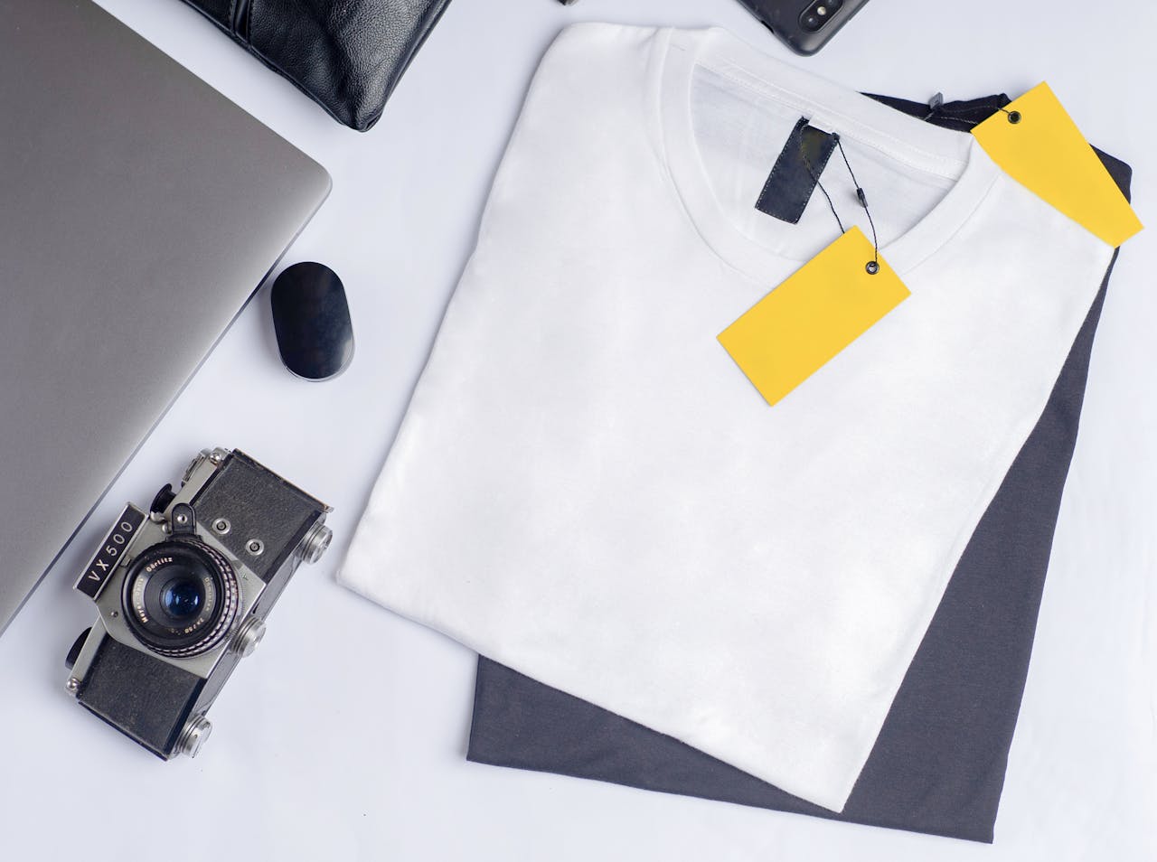 ours-journey Stylish flat lay featuring a vintage camera, clothing, and laptop on a clean white background.