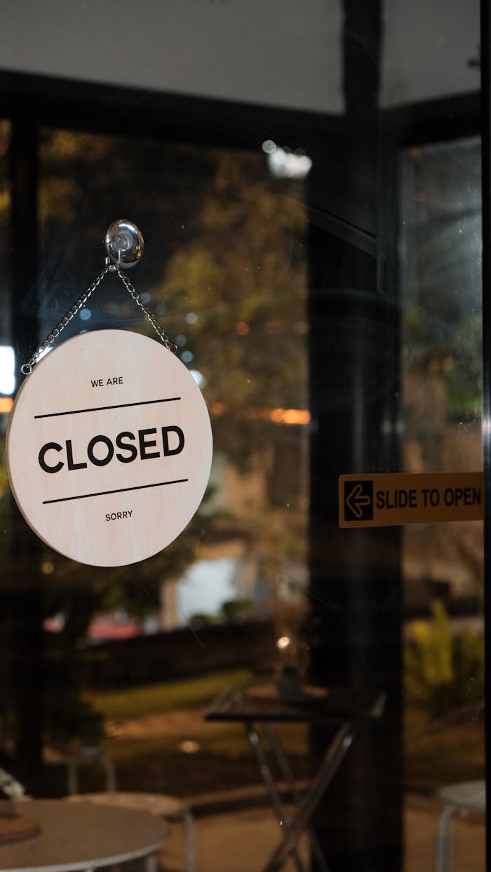 contact-img A glass door with a 'Closed' sign in a café at night, signifying closure.
