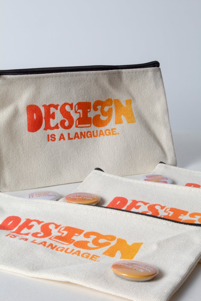 about-img Stylish canvas pouches featuring design quotes and colorful buttons against a minimalist backdrop.