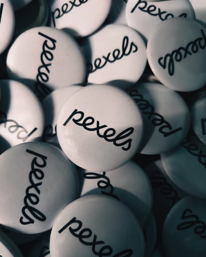 services-04 Close-up view of white Pexels logo buttons in shadowy lighting, creating a moody and artistic composition.