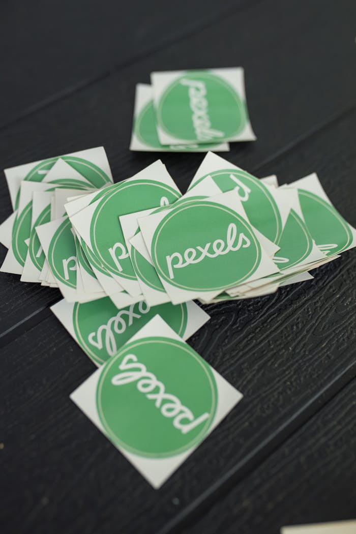 services-03 A scattered pile of green Pexels logo stickers on a textured dark surface, perfect for branding visuals.