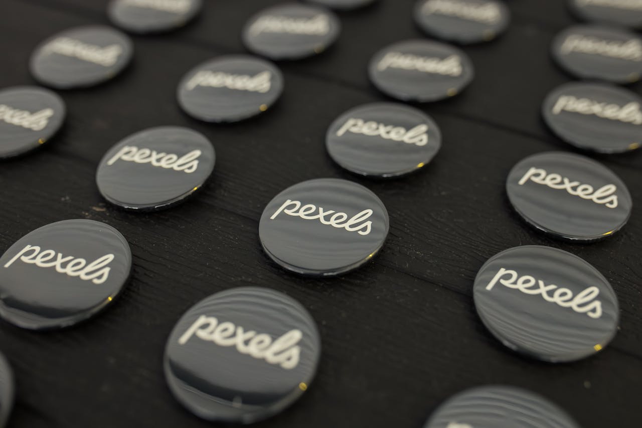 services-01 A close-up view of multiple Pexels logo buttons arranged neatly on a dark surface.