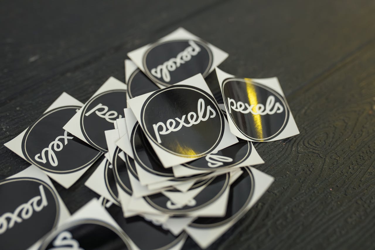 our-experience A collection of Pexels branded stickers scattered on a dark wooden surface.