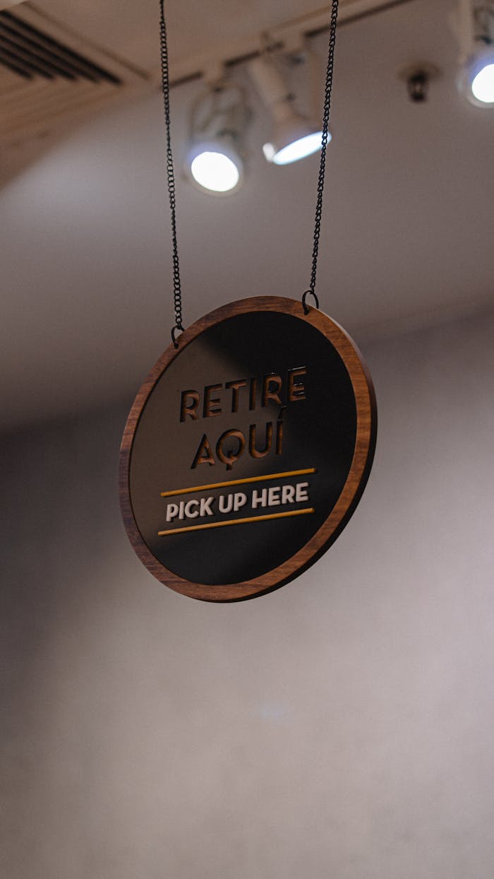 Stylish bilingual 'pick up here' sign indoors, offering clear service directions.