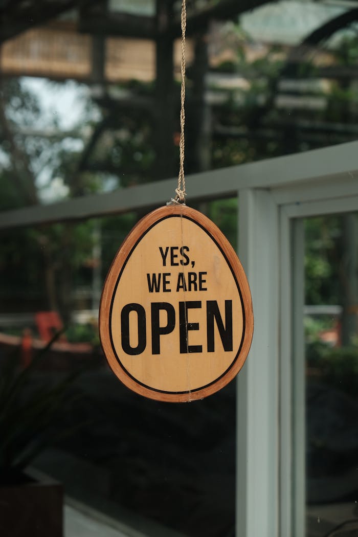 A rustic open sign in a storefront window, signaling welcome to customers.